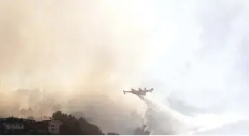  ?? — AFP photo. ?? A fire fighting Canadair aircraft drops water over a fire near Carros, southeaste­rn France.