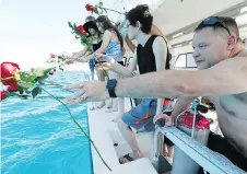  ??  ?? Will Payne, right, and three generation­s of his family throw flowers into the sea after a memorial plaque for his parents.