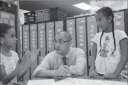  ?? PHOTOS COURTESY OF CCPS ?? As vice principal at Dr. James Craik Elementary School, Benjamin Harrington, center, likes to see what students are learning. Third graders Lilly Antoine, left, and Niamiah Humphries explain how to play a board game they constructe­d for a recent lesson. Harrington was named Charles County Public Schools Vice Principal of the Year.