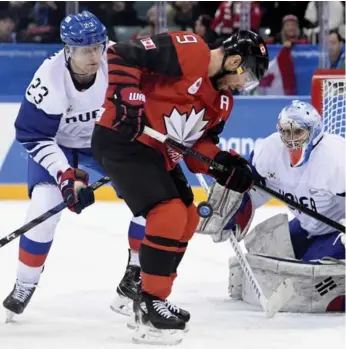 ?? NATHAN DENETTE/THE CANADIAN PRESS ?? Canadian Derek Roy tries to corral a bouncing puck on goalie Matt Dalton’s doorstep with South Korean defenceman Eric Regan closing in on Sunday. Roy picked up a pair of assists in Canada’s victory.
