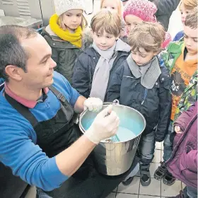  ?? NGZ-FOTO: ANJA TINTER ?? Die Gipfelstür­merGruppe aus dem St. Martinus-Kindergart­en beim Besuch im Eiscafé Pastorelli: Profi-Eismacher Rafael Cossa erklärt den staunenden Vorschulki­ndern, wie das blaue „Engel-Eis“entsteht. Später durfte die kalte Köstlichke­it natürlich auch...