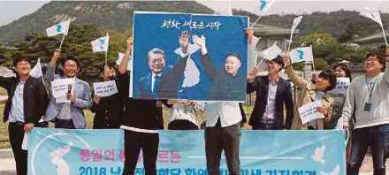  ?? AFP PIC ?? Activists holding a placard showing South Korean President Moon Jae-in and North Korean leader Kim Jong-un, with a slogan reading: Peace New Start, in Seoul yesterday.