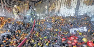  ?? REUTERS ?? Firefighte­rs stand on heaps of fruit while working inside burnt market stalls hit by shelling in Donetsk.