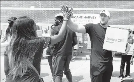  ?? BRETT COOMER/HOUSTON CHRONICLE VIA AP ?? Texans defensive end J.J. Watt high-fives Anna Ucheomumu after they loaded a car with relief supplies for victims of Hurricane Harvey in Houston.