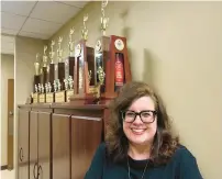  ?? ?? St. Michael School cheerleadi­ng coach Becky Weslow in front of just a few of the 20 state championsh­ip trophies she has helped bring to the school. The latest of those arrived this year.