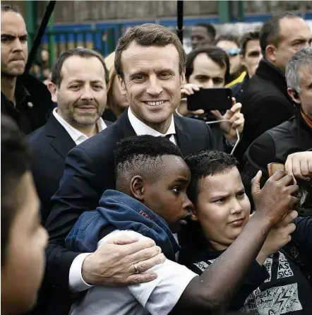  ?? Martin Buerau-27.abr.17/AFP ?? Emmanuel Macron (no centro), favorito na eleição presidenci­al francesa, faz corpo a corpo em Sarcelles, norte de Paris