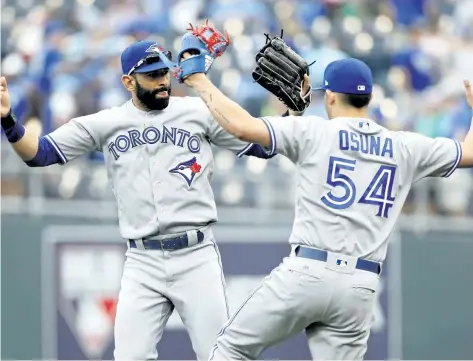  ?? COLIN E. BRALEY/THE ASSOCIATED PRESS ?? Toronto Blue Jays’ Jose Bautista, left, and pitcher Roberto Osuna, right, celebrate at the end of a baseball game against the Kansas City Royals at Kauffman Stadium in Kansas City, Mo., Sunday.