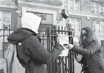  ?? MICHAEL M SANTIAGO/GETTY ?? School principal Jodie Cohen hands out masks in Brooklyn as in-person classes resumed Monday.