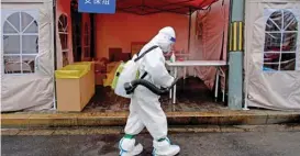  ?? (AFP) ?? A worker wearing personal protective equipment disinfects the entrance to a residentia­l area on lockdown due to the recent COVID-19 outbreaks in Beijing last week