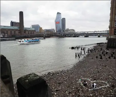  ?? The Associated Press ?? SELLING POINT: Volunteers work with a heart shaped collection of plastic bottles they and others made from bottles that were lying washed up nearby during a Feb. 9 media event organized by the #OneLess campaign and Thames21 London waterways charity to...
