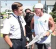  ??  ?? United Airlines pilot Steve Spooner, left, of Old Lyme, speaks with former flight attendant Paul “Paulie” Veneto, who is pushing an airline beverage cart from Boston’s Logan Airport to Ground Zero in New York City.