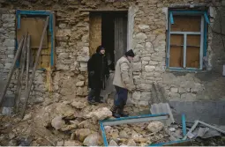  ?? DANIEL COLE/AP ?? Oleksandra Hryhoryna, left, inspects her house Saturday, damaged by shelling last fall in Kalynivske, Ukraine. Villagers are still suffering with no electricit­y or water.