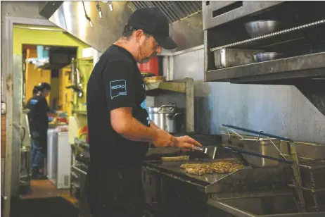  ?? ?? Ky Quintanill­a cooks up food on the grill at El Conejo, where he has landed as head chef after a months-long trip to Mexico.