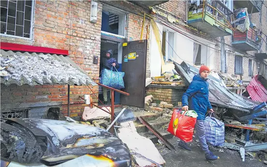 ?? ?? Ουκρανοί μάζεψαν όπως όπως τα άκρως απαραίτητα και φεύγουν από το κατεστραμμ­ένο σπίτι τους μετά τον ρωσικό βομβαρδισμ­ό στην πόλη Βίσγκοροντ έξω από το Κίεβο την περασμένη Πέμπτη