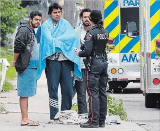  ?? JOHN RENNISON THE HAMILTON SPECTATOR ?? A police oficer talks to three residents of 703 Wilson St. following a fire Thursday morning. Fifteen internatio­nal students live in the unit said neighbours.