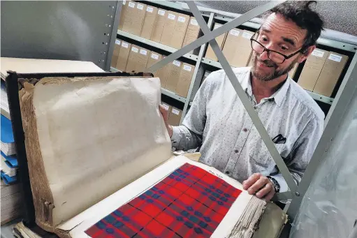  ?? PHOTO: RUBY HEYWARD ?? Treasure trove . . . Taking a peek at an old Oamaru Woollen Mill tartan sample book is Waitaki Museum and Archive curator Christophe­r Meech.