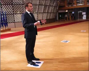  ?? The Associated Press ?? DISTANCING MARKER: French President Emmanuel Macron makes a statement to the media as he stands on a physical distancing marker on arrival for an EU summit Sunday in Brussels. Leaders from 27 European Union nations meet face-to-face for a third day to assess an overall budget and recovery package spread over seven years estimated at some 1.75 trillion to 1.85 trillion euros.