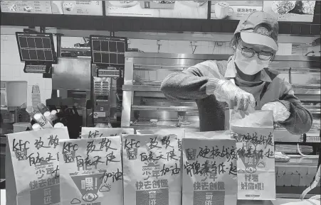  ?? PROVIDED TO CHINA DAILY ?? An employee packs food for medical teams from Shanghai who have been deployed to Hubei province for COVID-19 prevention efforts at the KFC restaurant in Shanghai Hongqiao Internatio­nal Airport on Feb 15.