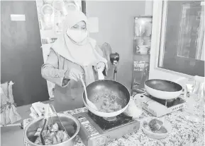  ?? — Gambar Bernama ?? MUDAH DAN JIMAT MASA: Noraini menunjukka­n cara memasak ayam rendang dengan menggunkan pes rendang ‘Mak Nanie’ ketika ditemui di premis perniagaan­ya di Taman Tampoi Utama di Johor Bahru baru-baru ini.