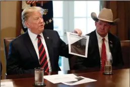  ?? The Associated Press ?? WHITE HOUSE: President Donald Trump holds a photo as he leads a roundtable discussion on border security with local leaders Friday in the Cabinet Room of the White House in Washington.