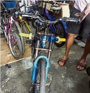  ??  ?? Extreme modificati­on: A cyclist fixing handle stands (yellow) on the lower part of the downhill suspension fork and removing the original handlebars on top, to lower the bicycle. Right: A young cyclist showing off his wheelie skills.