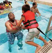  ??  ?? A Lee Elementary School student jumps into the arms of volunteer Anthony Waddell during the Wee Water Wahoo event Friday at the Rose State College Aquatic Center in Midwest City.