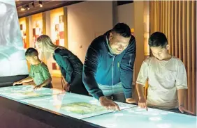  ?? ?? Visitors check out the waka table at Te Ko¯ngahu Museum of Waitangi. Photo / Supplied