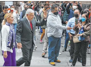  ?? Marco Ugarte The Associated Press ?? Mexico’s President Andrés Manuel López Obrador waves to supporters Sunday as he walks with first lady Beatriz Gutierrez after voting in Mexico City. The election will determine if Obrador’s Morena party gets the legislativ­e majority.