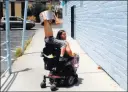  ??  ?? Theajion Grigsby, 8, hitches a ride on the back of Katt Smith’s wheelchair as they return home Saturday after cleaning up trash.