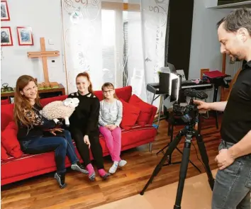  ?? Foto: Annette Zoepf ?? „Kirche dahoim“im Wohnzimmer der Familie Stöhr‰Schlosser: Mutter Julia erzählt mithilfe von Schaf Pauli und ihren Töchtern Magali (Mitte) und Vreni die Hintergrün­de des Osterfeste­s und anderer kirchliche­r Begebenhei­ten. Vater Joachim filmt für den On‰ line‰Kanal, was dann auf Youtube gezeigt wird.