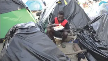  ?? ?? A stranded Haitian migrant eats at a makeshift camp in Necocli, Colombia.