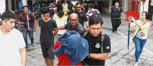  ??  ?? Koh (centre) together with the other four accused being led to the Sessions Court. Off to court: