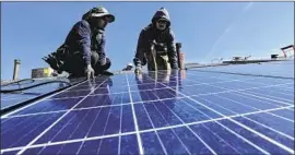  ?? Irfan Khan Los Angeles Times ?? GEORGE GONZALEZ, left, and Hector Maldonado install solar panels. Solar installers urged the state to keep a requiremen­t for solar panels on new homes.