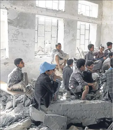  ??  ?? Children assemble in their bombed school, above, and a girl in a hospital in capital Sanaa, below