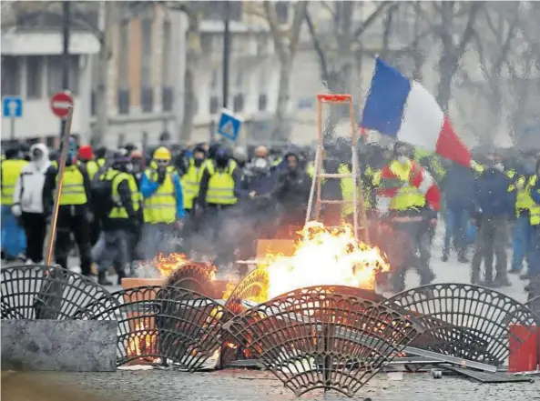  ?? Fotos: Efe ?? ‘Chalecos amarillos’ se situaban tras las barricadas de fuego improvisad­as cerca de la avenida de los Campos Elíseos de París.