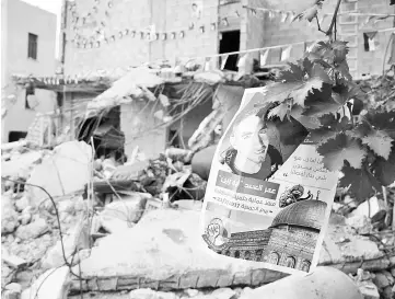  ??  ?? A poster bearing the picture of Abed hangs outside his family home after it was demolished by Israeli authoritie­s in the West Bank village of Kobar, near Ramallah. Arabic writings read “the hero who carried out the Halamish operation”. — AFP photo