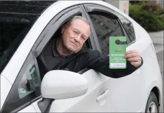  ?? Daily Courier file photo ?? Gary Brown holds his Eco-Pass while parked along Doyle Avenue in his 2010Toyota Prius hybrid.The City of Kelowna has refused to renew his pass, which had allowed him free parking.