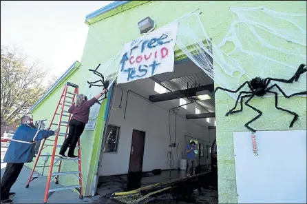  ?? PHOTOS BY JENNY SPARKS / Loveland Reporter-herald ?? Laura Marsh, a Speedy Sparkle car wash employee, adjusts a huge spider above the car wash entrance as co-worker Tone Archuleta holds the ladder Wednesday as they set up for a haunted tunnel at the car wash in Loveland.