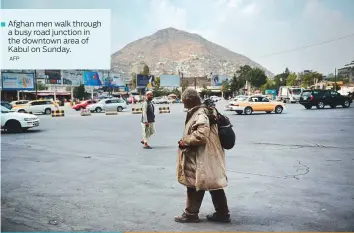  ?? AFP ?? Afghan men walk through a busy road junction in the downtown area of Kabul on Sunday.