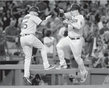 ?? Stephen Dunn Getty Images ?? AFTER HOMERING in the third inning, the Dodgers’ Joc Pederson, right, takes a moment to celebrate with third-base coach Chris Woodward as he rounds the bases. The Dodgers have homered in 16 straight games.