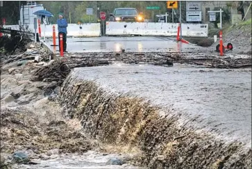  ?? Mark Boster For The Times ?? A SPECTATOR watches as rainwater f lows over the Trabuco Canyon Road bridge last month. “The reservoirs are full, lakes are full, the streams are f lowing, there’s tons of snow,” a federal climate scientist said.