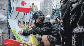  ?? GALIT RODAN THE CANADIAN PRESS ?? A man writes a message at a growing memorial on Yonge Street in Toronto on Tuesday.