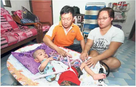  ??  ?? Worried parents: Ng and his wife tending to their son Yu Jian. The three-year-old needs assistance for his epilepsy surgery at the Ara Damansara Medical Centre.