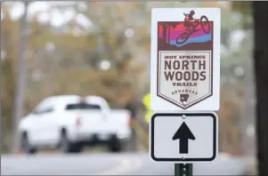  ?? The Sentinel-Record/Richard Rasmussen ?? TRAIL MARKER: A motorist drives along Cedar Glades Road near a sign pointing the way to the Hot Springs Northwoods Trails entrance. A public grand opening will be held for the first phase of the trail system Saturday at Cedar Glades Park.