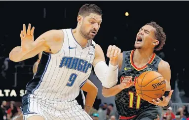  ?? KEVIN C. COX/GETTY ?? Atlanta Hawks guard Trae Young yells as he draws a foul from Magic center Nikola Vucevic while driving to the basket during Wednesday night’s game in Atlanta.