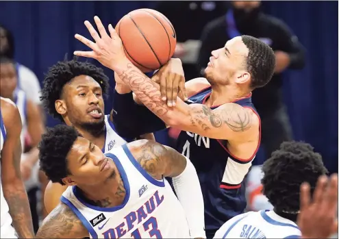  ?? Charles Rex Arbogast / Associated Press ?? UConn’s Tyrese Martin, right, battles DePaul’s Pauly Paulicap and Darious Hall (13) for the ball during Monday’s game.