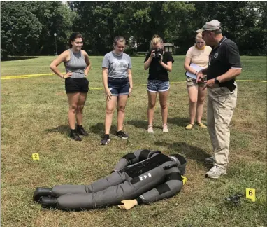  ?? GINGER RAE DUNBAR – MEDIANEWS GROUP ?? Downingtow­n Detective Paul “Andy” Trautmann, right, speaks to Downingtow­n STEM Academy students about how to process evidence at the mock crime scene.