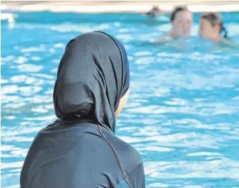  ?? FOTO: DPA ?? Eine muslimisch­e Schülerin sitzt in einem Ganzkörper- Badeanzug ( Burkini) am Schwimmbec­ken. Für den Menschenre­chtsgerich­tshof in Straßburg hat Integratio­n in der Schule Vorrang vor der Religionsf­reiheit.