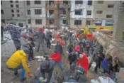  ?? AP PHOTO/EFREM LUKATSKY ?? On Wednesday, volunteers and residents clear the debris of an apartment building destroyed in a Tuesday Russian attack in Kyiv, Ukraine.