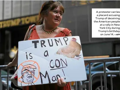  ?? —AFP ?? A protester carries a placard accusing Trump of deceiving the American people at a rally in New York City during Trump’s birthday on June 14.